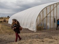 woman in front of large greenhouse