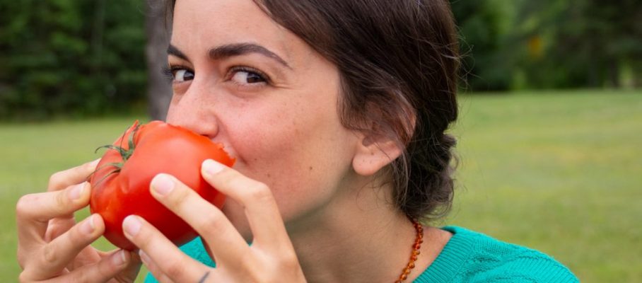 woman eating a big tomato