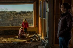 woman watching her children play by window in house under construction
